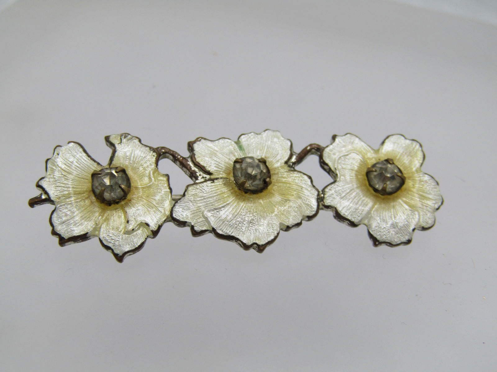 Vintage Guilloche Triple Blossom Brooch, Rhinestones, 2" - C-Clasp: Vintage Guilloche Triple Blossom Brooch, Rhinestones, 2" wide and 5/8" tall - C-Clasp. This has a pointed c-clasp like the tip of a torpedo. It is a silver tone cast metal. Three white and