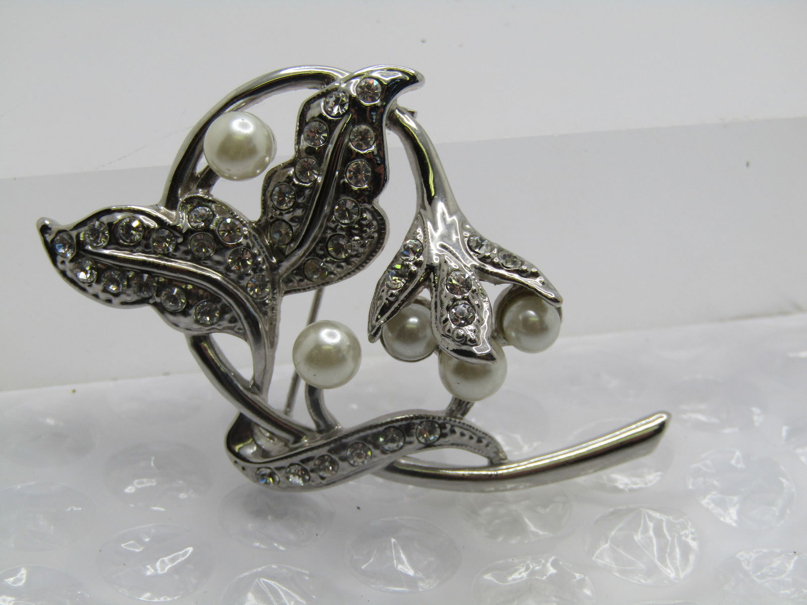 Vintage Faux Pearl & Rhinestone Leaf Stem Brooch, 1980's-1990's: Vintage Faux Pearl & Rhinestone Leaf Stem Brooch, 1980's-1990's This has a smooth curled stem with leaves and a blossom on top - the leaves have rhinestones set in to them as well as the cap of the