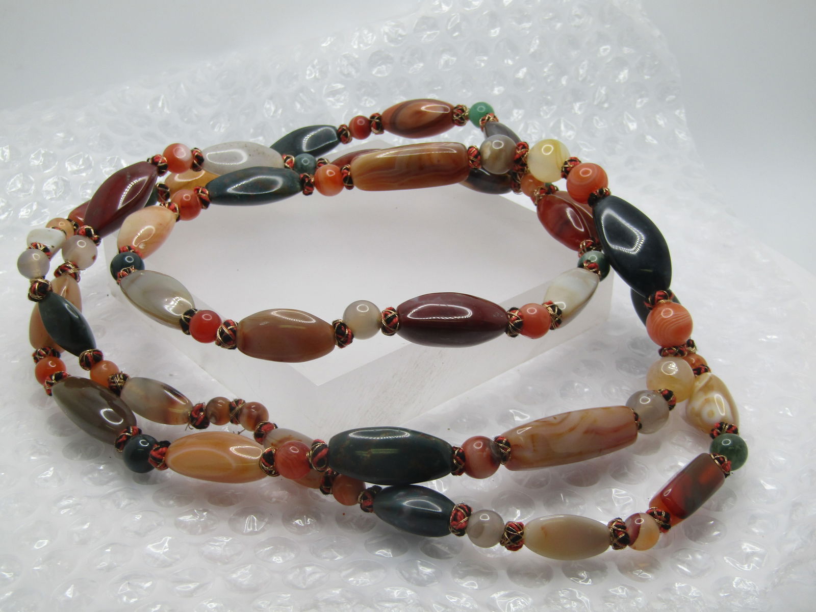 Vintage 52" Hardstone Necklace, Earthtones, 1970's-1980's: Vintage 52" Hardstone Necklace, Earthtones, 1970's-1980's. Slipover design with orange and gold wire wrapped cushions between the stones. Polished agates/jaspers in green, white, gray, brown, amber,