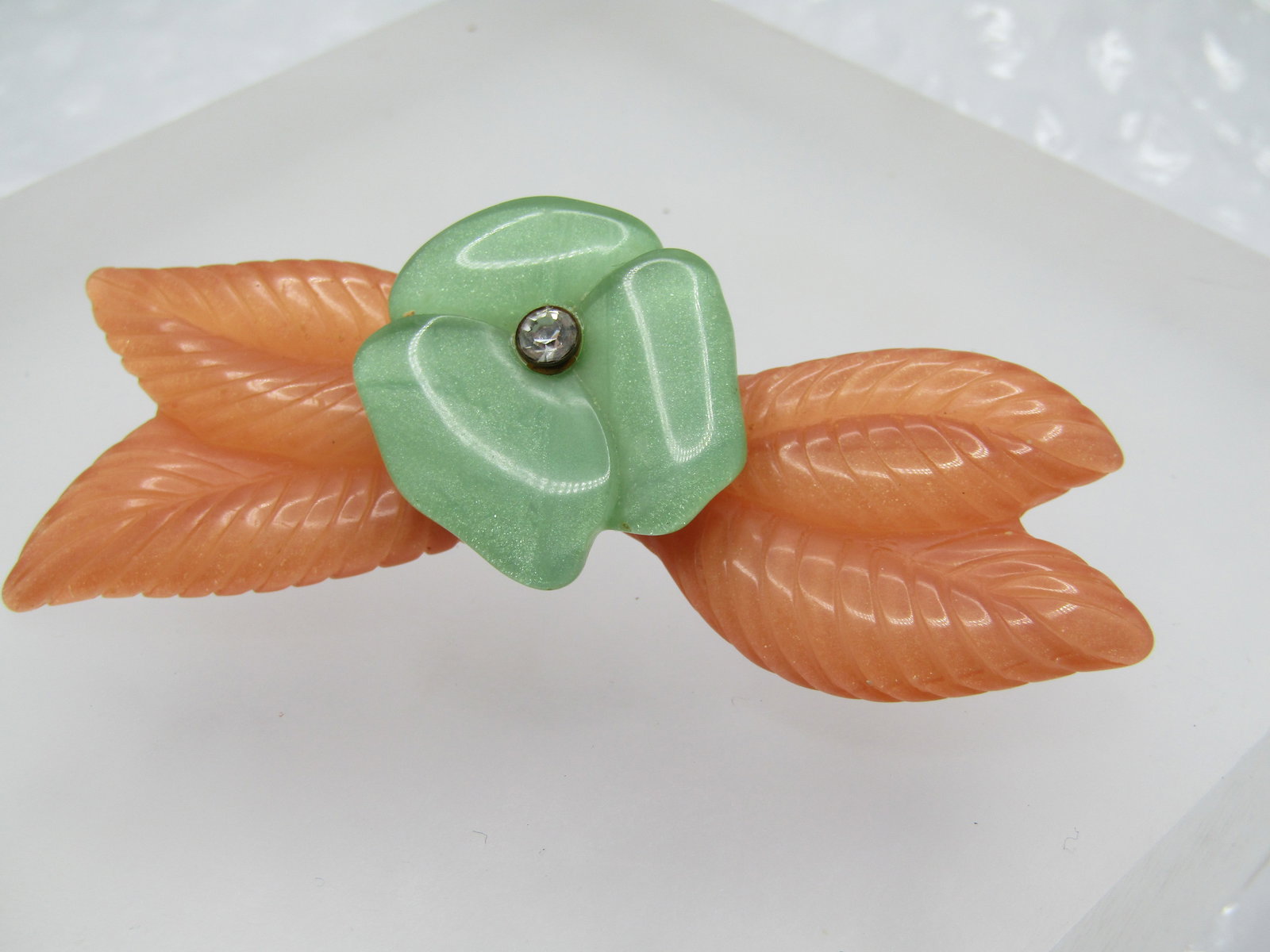 Vintage Celluloid Floral Brooch with Rhinestone. 2.5",: Vintage Celluloid/Plastic Floral Brooch with Rhinestone. 2.5" long and 1" tall. It has a orange background with a clearer top with leaf detailed on the top surface and on top of that is a green back