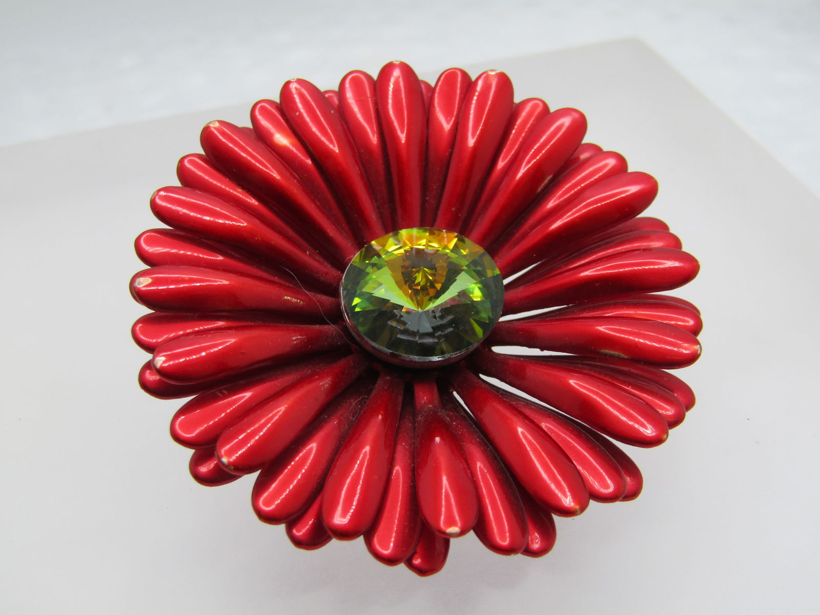 Vintage Red Gerbera Daisy Brooch, Rivoli Crystal Center, 2": Vintage Red Gerbera Daisy Brooch, Rivoli Crystal Center, 2" Tiered candy apple enameled petals that are lower in the center where a bezel-set green/yellow round and pointed rivoli crystal/rhinestone t