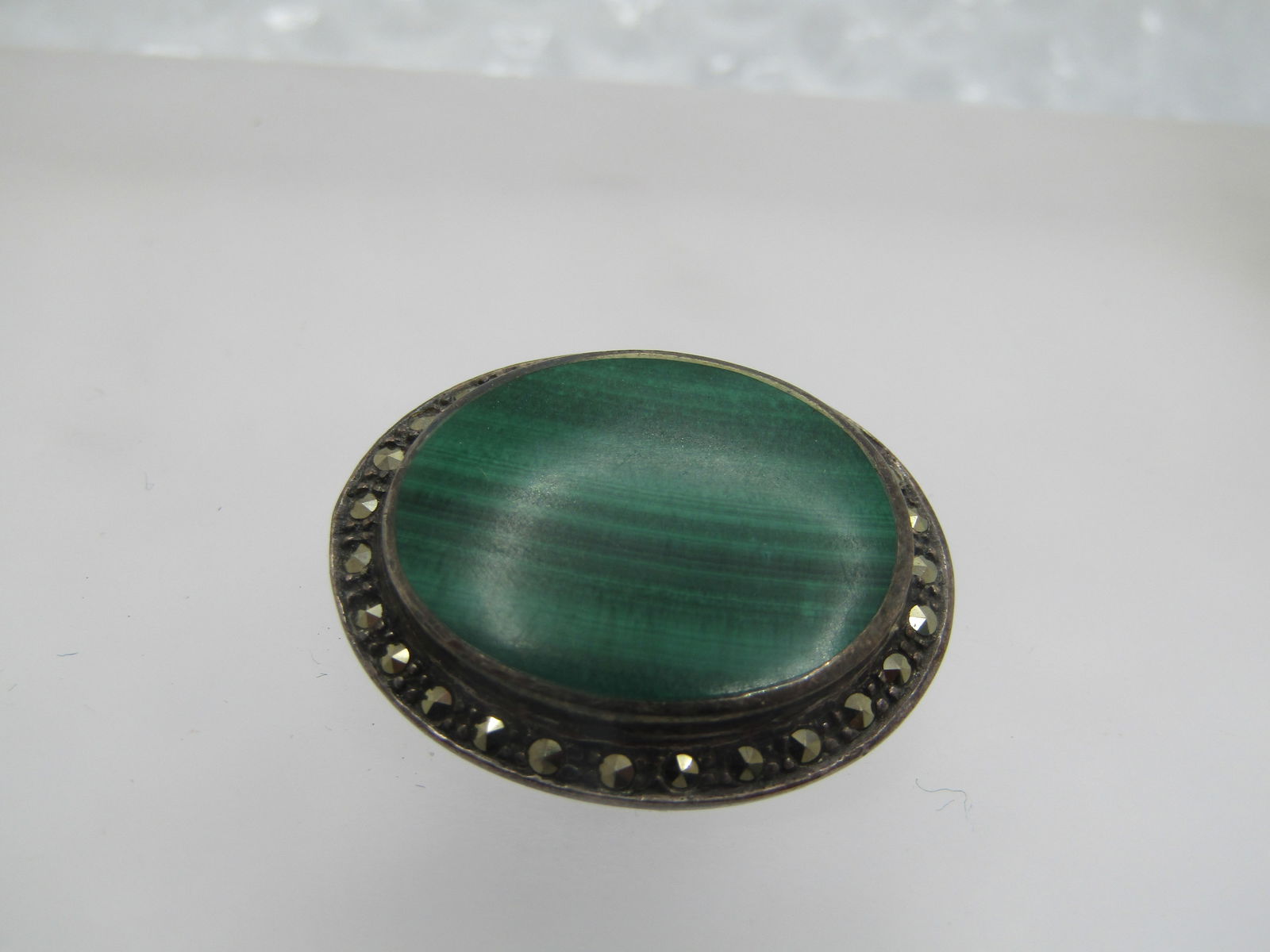 Vintage Sterling Malachite Marcasite Brooch, 1970's-1980's: Vintage Sterling Malachite Marcasite Brooch, 1970's-1980's. It is a bezel-set oval malachite that is appx. 22mm by 18mm with a lower frame of marcasites. The brooch is iappx. 1-1/8" by 1". It is
