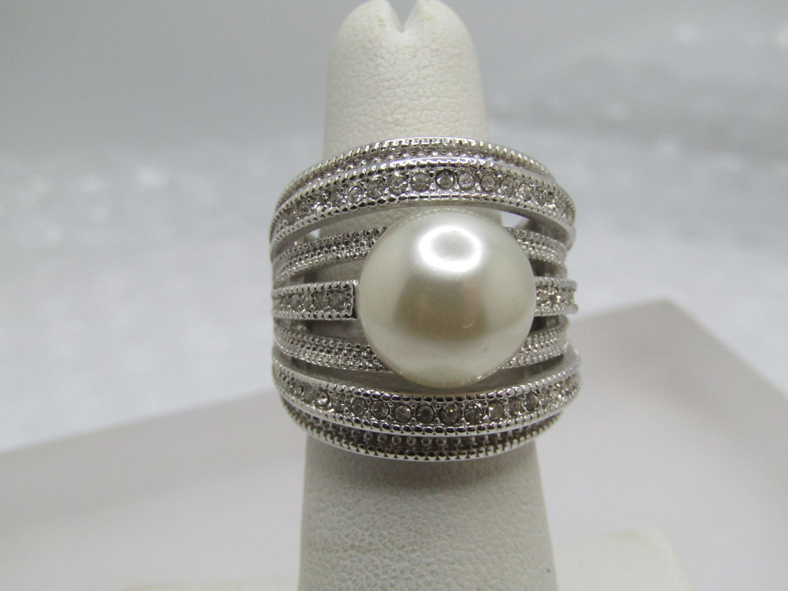 Silver Tone Faux Pearl Statement Ring, Sz. 5-7, Clear Stones, Signed: Silver Tone Faux Pearl Statement Ring, Sz. 5-7, Clear Stones, Signed NVC w hich is Nataliya Collister. This is a costume ring that is appx. 22.5m wide going down the finger with alternating higher