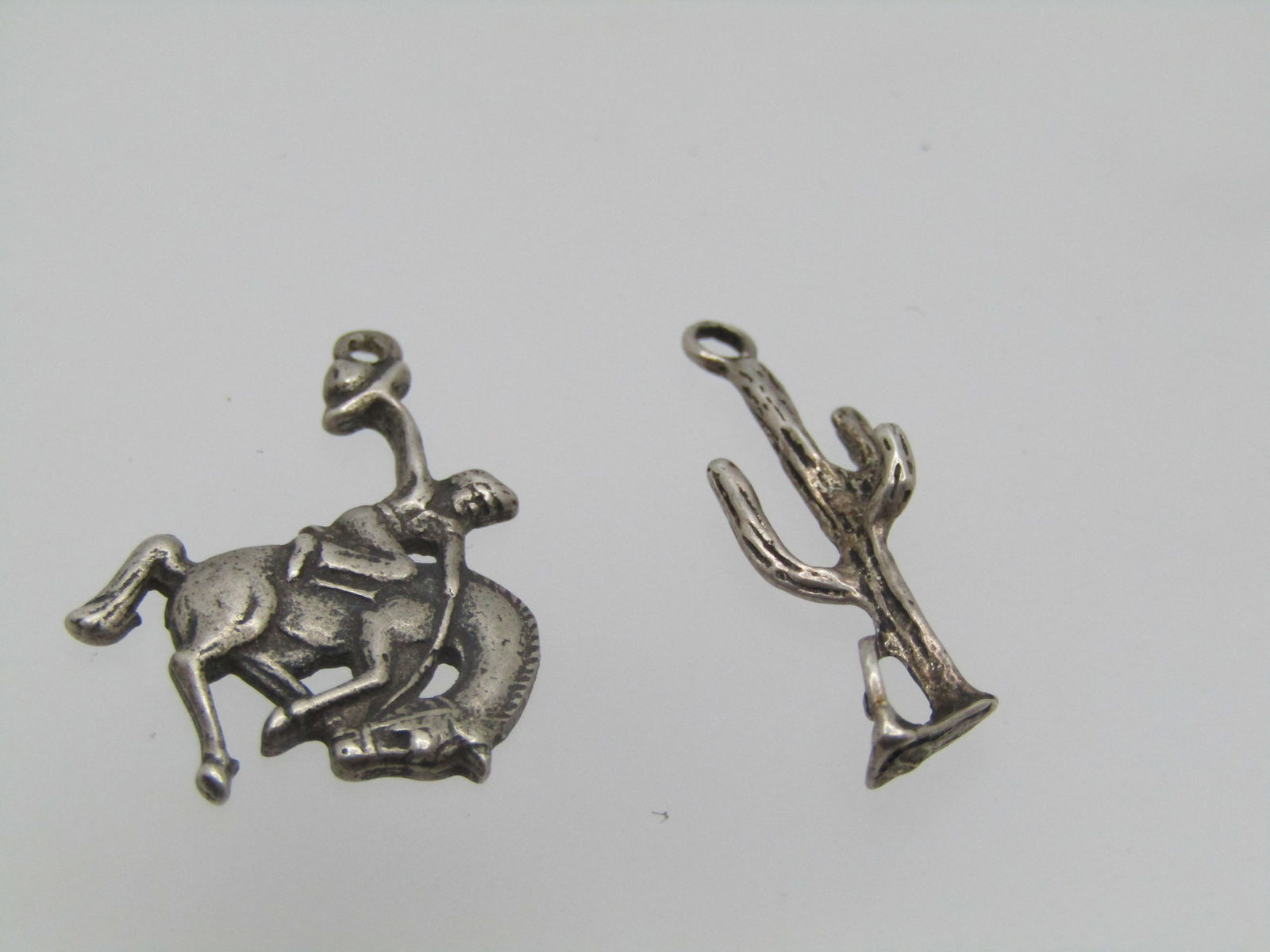 Vintage Sterling Bronco Rider & Cactus Charms/Pendants, 1960's-1980's: Vintage Sterling Bronco Rider & Cactus Charms/Pendants, 1960's-1980's. The cactus is marked but cannot be read. It is appx. 7/8" tall and 1/3" wide with several branches to the cactus with a broken