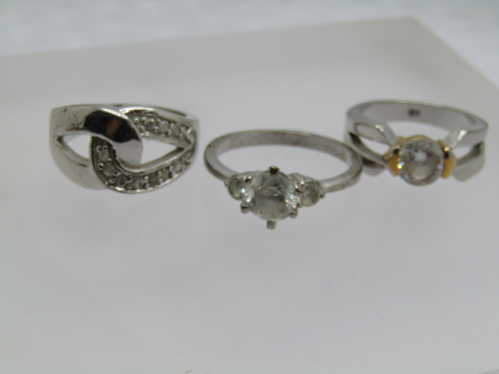 Three Silver Plated Rhinestone Rings, Sz. 7 and 9: Three Silver Plated Rhinestone Rings, Sz. 7 and 9. Great for resale or wear. The sz. 9 is a three clear stone engagement ring style - it is not marked or signed. There is a size 7 silver tone with gol