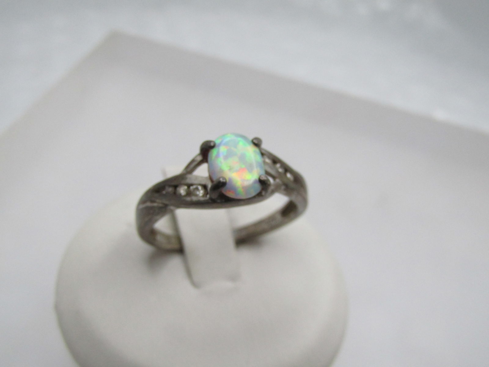Vintage Sterling Created Opal & CZ Ring, Sz. 8.75, Signed RJ: Vintage Sterling Created Opal & CZ Ring, Sz. 8.75, Signed RJ. The opal which is a created oap, is appx. 7.5mm by 6mm oval. Four prongs hold the opal. The band has a bypass design with channel set appx