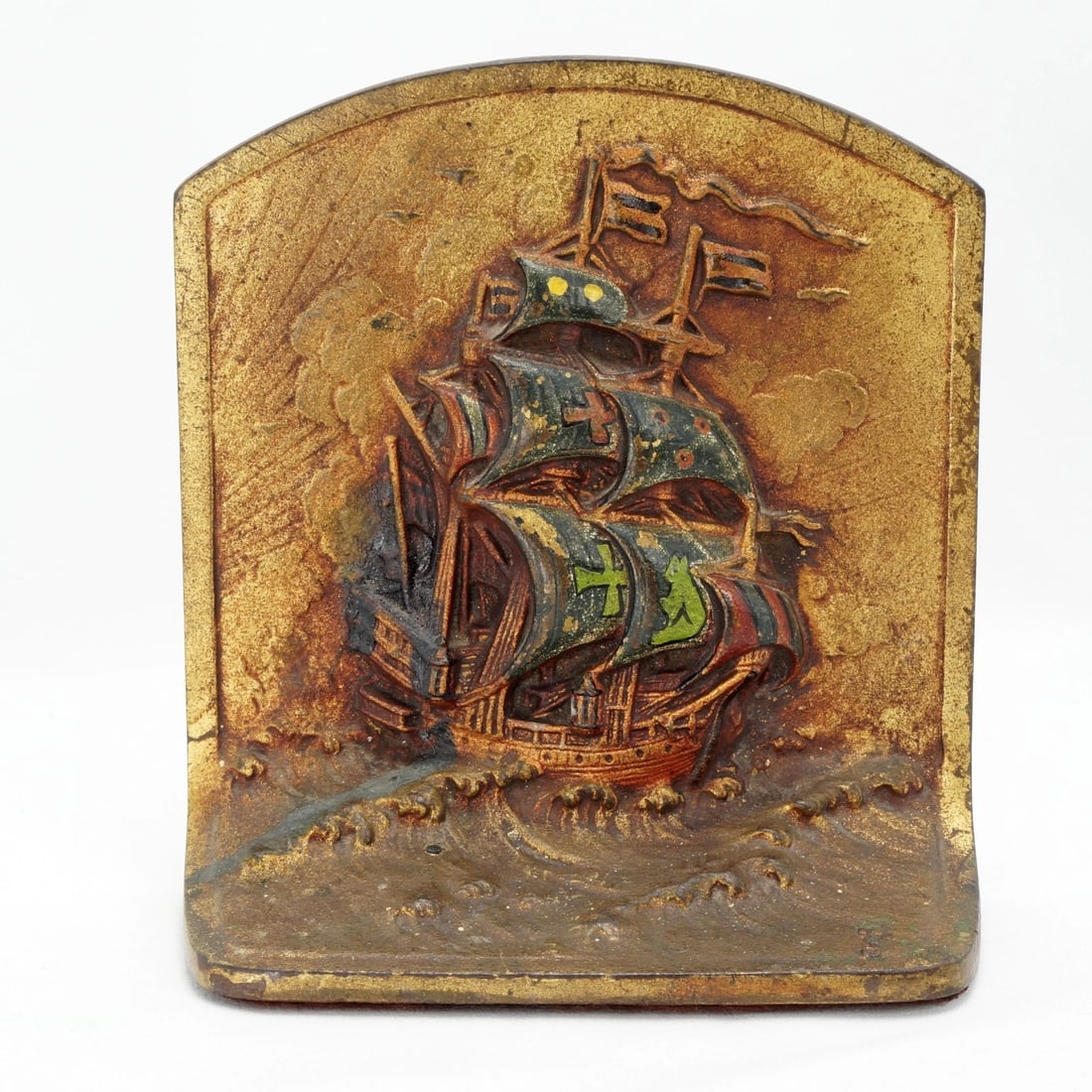 Single Ship at Sunrise Iron Bookend circa 1925: Title:Single Ship at Sunrise Iron Bookend circa 1925Size:5 in (12.7 cm) wide x 2 in (5.1 cm) deep x 5 1/2 in (14.0 cm) tall.Description:A colorful and deeply cast polychrome cast iron single bookend