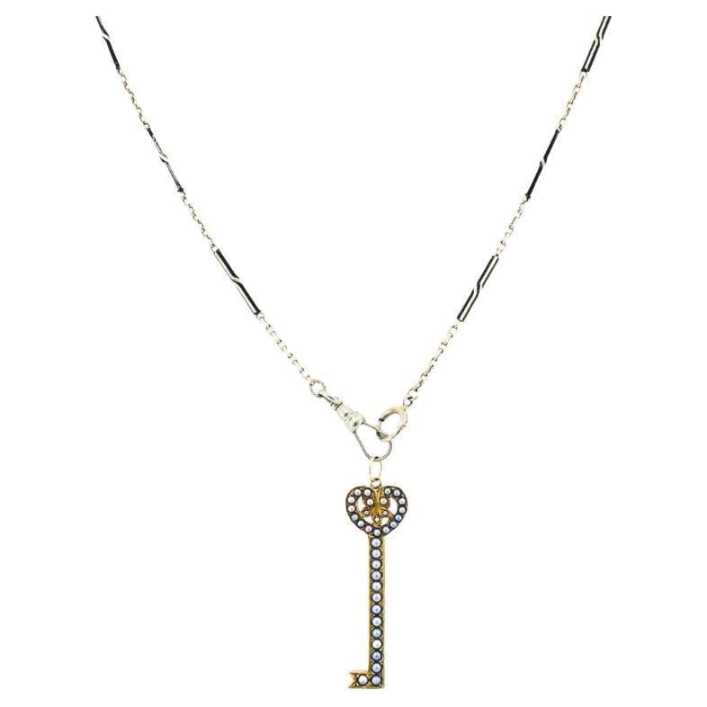 14k Gold Key Pendant Necklace Pearls and Black Enamel: About the Item Materials: 14k Gold, Enamel Weight: 9.6 Grams Gemstone: Pearl Measurement: Pendant - 1/2" x 1 1/2" Chain - 13 1/2" Hallmarks: 14 KT ITEM DETAILS: This 14k gold necklace features a