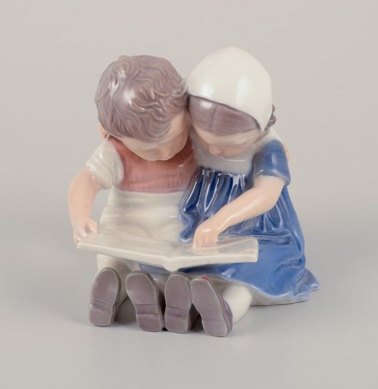Bing & Grøndahl, Denmark. Porcelain figurine of reading children. Approximately 1930s.: Title: Bing & Grøndahl, Denmark. Porcelain figurine of reading children. Approximately 1930s. Description: Bing & Grøndahl, Denmark. Porcelain figurine of reading children. Model no. 1567. A