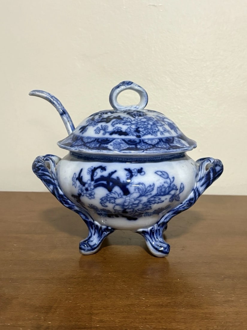 3pc Flow Blue Sauce Tureen: The tureen measures 7 5/8” x 5 3/4” x 6 5/8” high. It has no chips, cracks or repairs. The ladle measures 5 1/2” long x 3”. It handle has been reglued. Otherwise it has