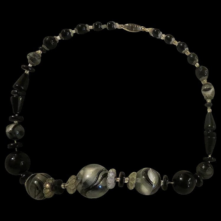 Early Antique Black Swirl Glass Beads: An early beaded necklace with large black glass beads featuring a distinct center seam and marble-like swirling. Shipping:Domestic: Flat-rate of $10.00 to anywhere within the contiguous