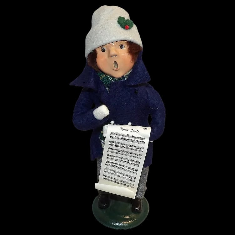 Byers Choice 1986 Boy with Music: Vintage 1986 Byers Choice boy caroler holding 'Joyeux Noel' sheet music. Stands 9 ½” tall and features a blue tailcoat and scarf. Shipping:Domestic: Flat-rate of $15.00 to anywhere within