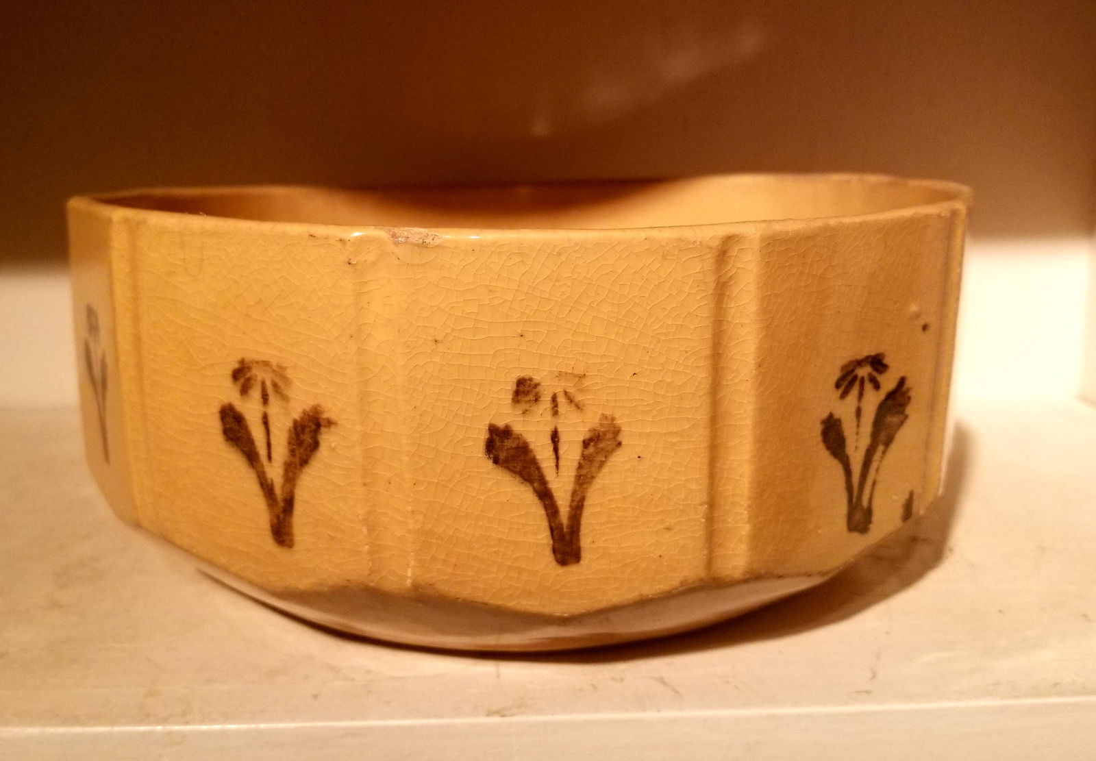 Yellowware pudding dish, panelled with stamped geometric flowers: Greeny black ink. 9 1/2" diameter. A faint line and wear on the rim. Yellowware is a soft-bodied pottery so it can damage. All pieces can be used, table service. 
