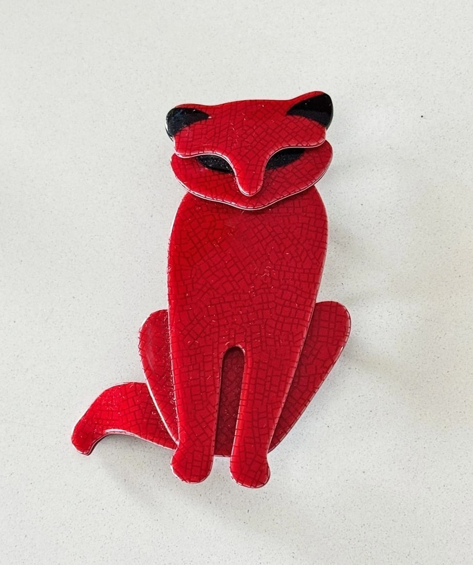 Signed Lea Stein Red Sacha Cat Brooch: An red Sacha the Cat brooch by French designer Lea Stein who along with her husband, Fernand, developed an innovative technique of layering thin cellulose sheets and then laminating the piece to