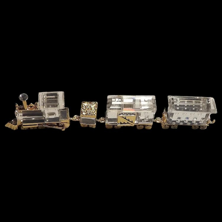 Swarovski 4 Piece Crystal Memories Train Set: Swarovski miniature train set including Locomotive, Tender, Wagon, and Petrol Wagon. Clear faceted crystal with gold-tone accents. Boxed set. Item ID: ls009678. Shipping:Domestic: Flat-rate of