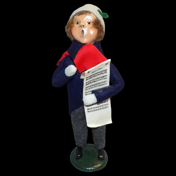 Byers Choice 1987 Boy with Music: Vintage 1987 Byers Choice boy caroler holding 'Joyeux Noel' sheet music. Features a blue tailcoat and stands 9 ½” tall. Shipping:Domestic: Flat-rate of $15.00 to anywhere within the