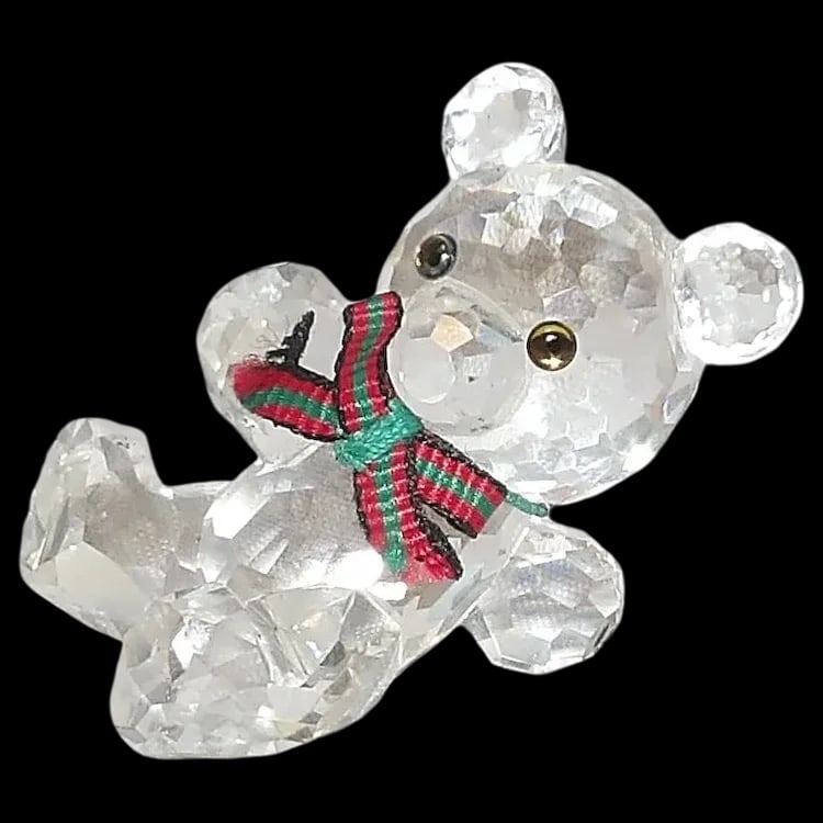 Swarovski Silver Crystal Kris Bear Figurine: Retired Swarovski crystal Kris Bear with a green and red bow. Comes in original box with COA. Stands 1 ½” tall. Shipping:Domestic: Flat-rate of $15.00 to anywhere within the contiguous