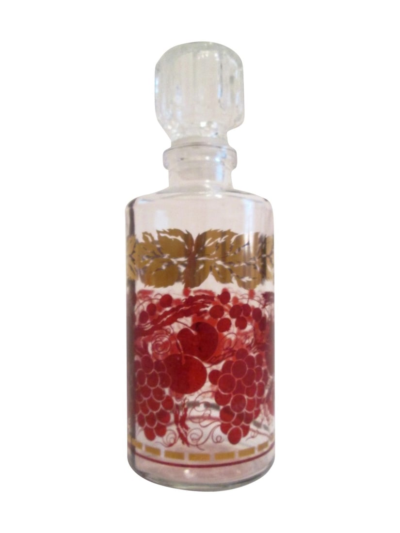 French Gold-Gilt Liquor Decanter: Pretty vintage French clear glass decanter featuring a fruit vine-motif in a deep shade of burgundy around perimeter with gold accents. Glass topper with plastic-twist seal. Marked underside