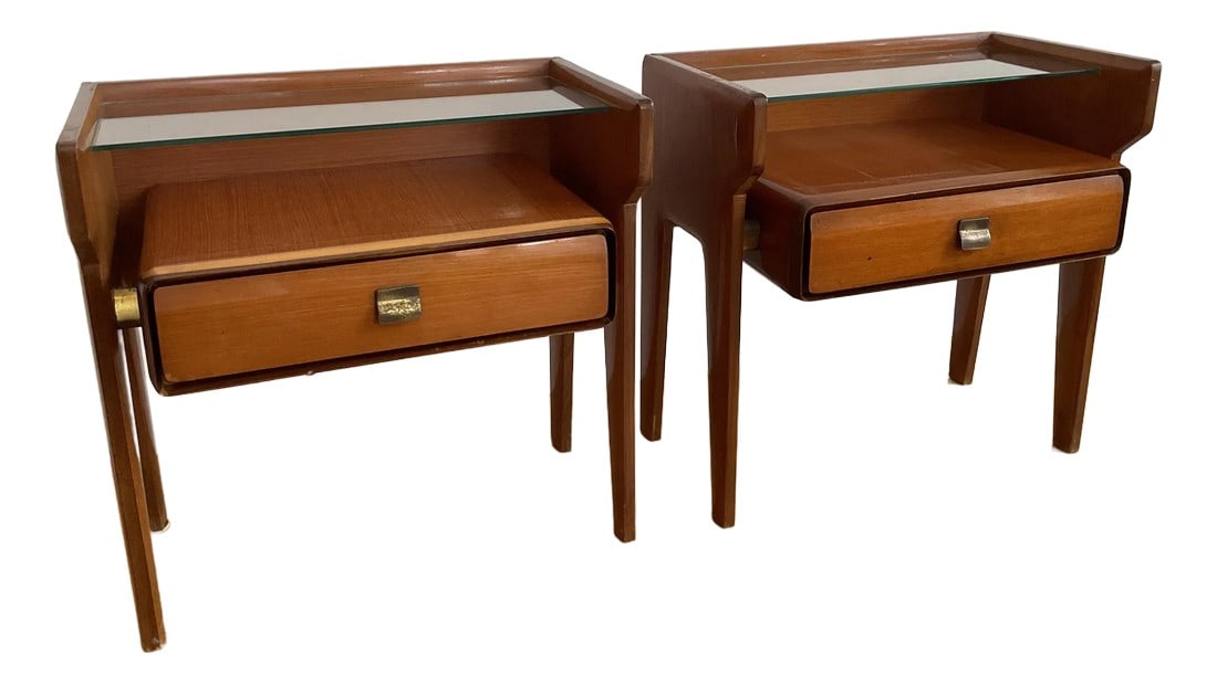 Vittorio Dassi 1950s Side Tables, a Pair: Circa 1950, mahogany veneer, upper inset glass shelf over a lower drawer with original shaped brass pull, tapered legs, unmarked. Professional repair was done to one table: the top left corner of the