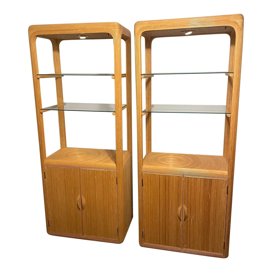 1970s Gabriella Crespi Pencil Reed Lighted Etagere With Two Door Storage: Pair of fantastic natural toned Gabriella Crespi inspired etageres with glass shelves and additional shelving behind double doors. The pair are in overall good shape for their age. The glass shelves
