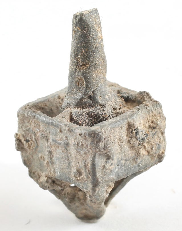 LATE MEDIEVAL DREIDEL, 16th-17th CENTURY: 1" height. Heavy lead-based alloy. Four veins, each with a curved open bar below converging to form the point. Box form body with Hebrew ciphers each side. Tapered grip to the top. Some oxidation and