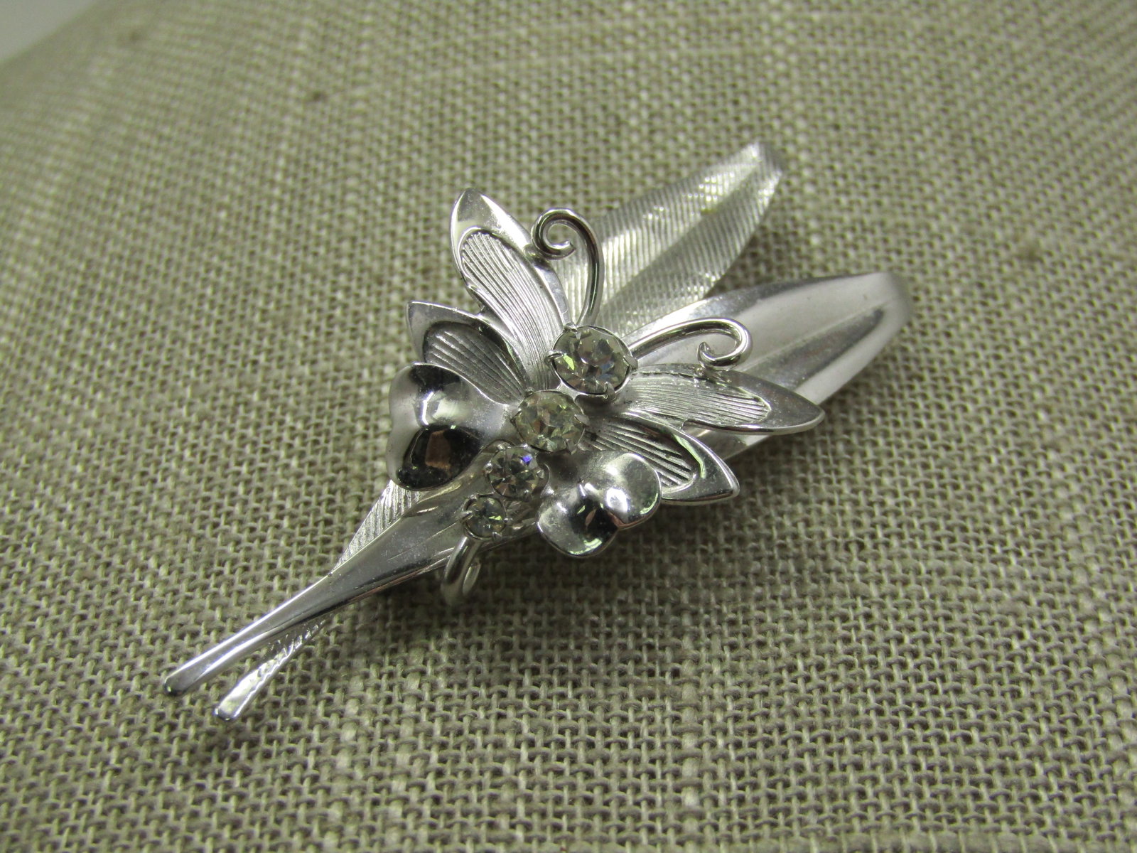 Vintage Sterling Butterfly & Leaves Brooch, Signed SKL, 6.29 gr.: Vintage Sterling Butterfly & Leaves Brooch, Signed SKL, 6.29 gr., 1960's. The The 1" butterlfy with rhinestone torso is sitting on one smooth and one textured slender leaf. The brooch is 2.25" tall an