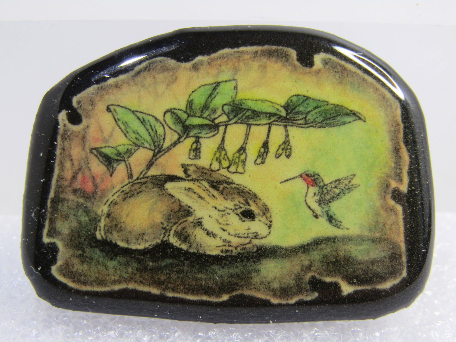 Vintage Bunny & Hummingbird Brooch, Under Branch 1980's-1990's: Vintage Bunny & Hummingbird Brooch, Under Branch 1980's-1990's. This is a printed image scene with a deliberately tattered edge shet under a thick, clear shiny liminated top. The base is a black plast