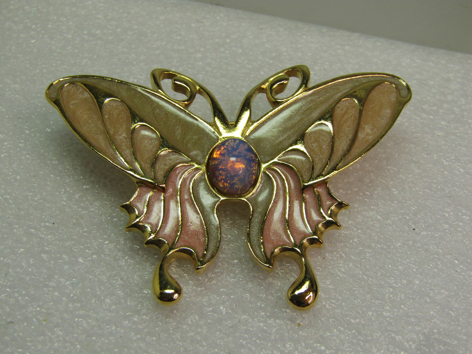 Vintage Enameled Faux Opal Butterfly Brooch, 1980's: Vintage Enameled Faux Opal Butterfly Brooch, 1980's. Gold tone pearly enameled brooch in tan and peach with a faux opal torso. The brooch is appx. 2.5" by 1.75" at the widest point. The enameling is r