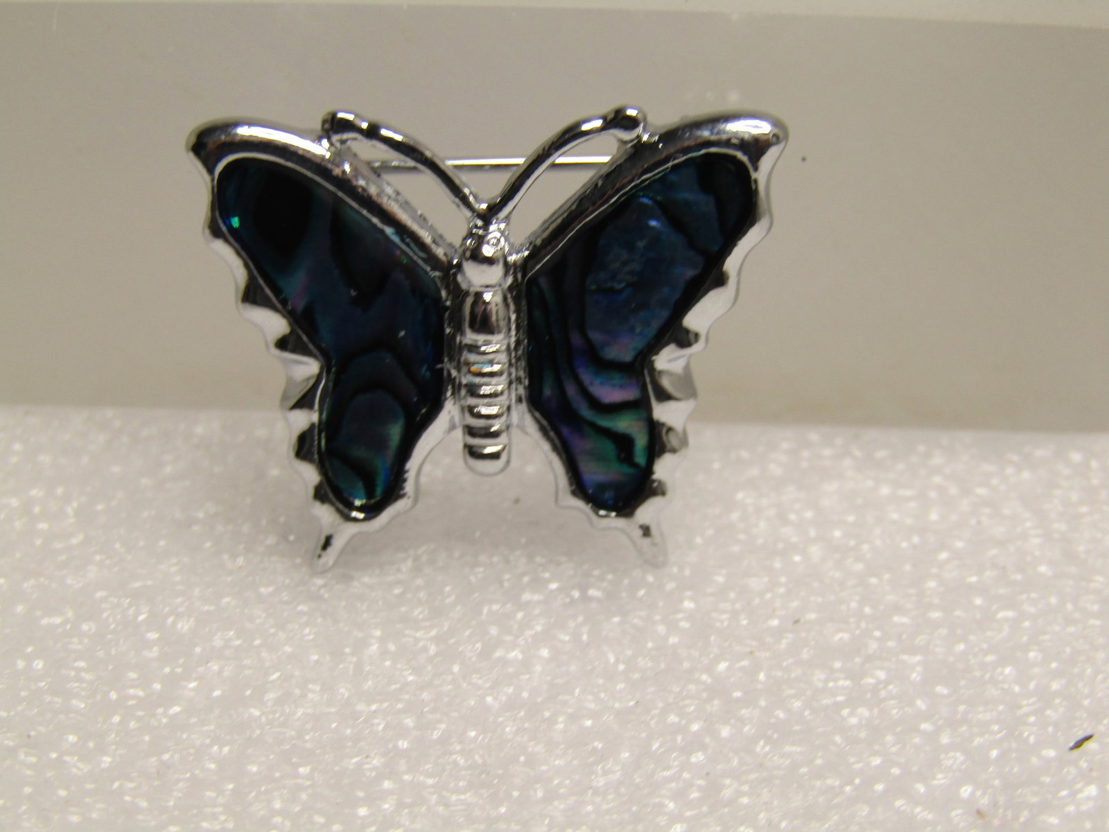 Vintage Faux Abalone Butterfly Brooch, Silver Tone, 1980's-1990's: Vintage Faux Abalone Butterfly Brooch, Silver Tone, 1980's-1990's. The brooch is silver tone and appx. 1" tall and 7/8" wide with inlaid abalone colored laminated wings. It has a locking clasp. It is