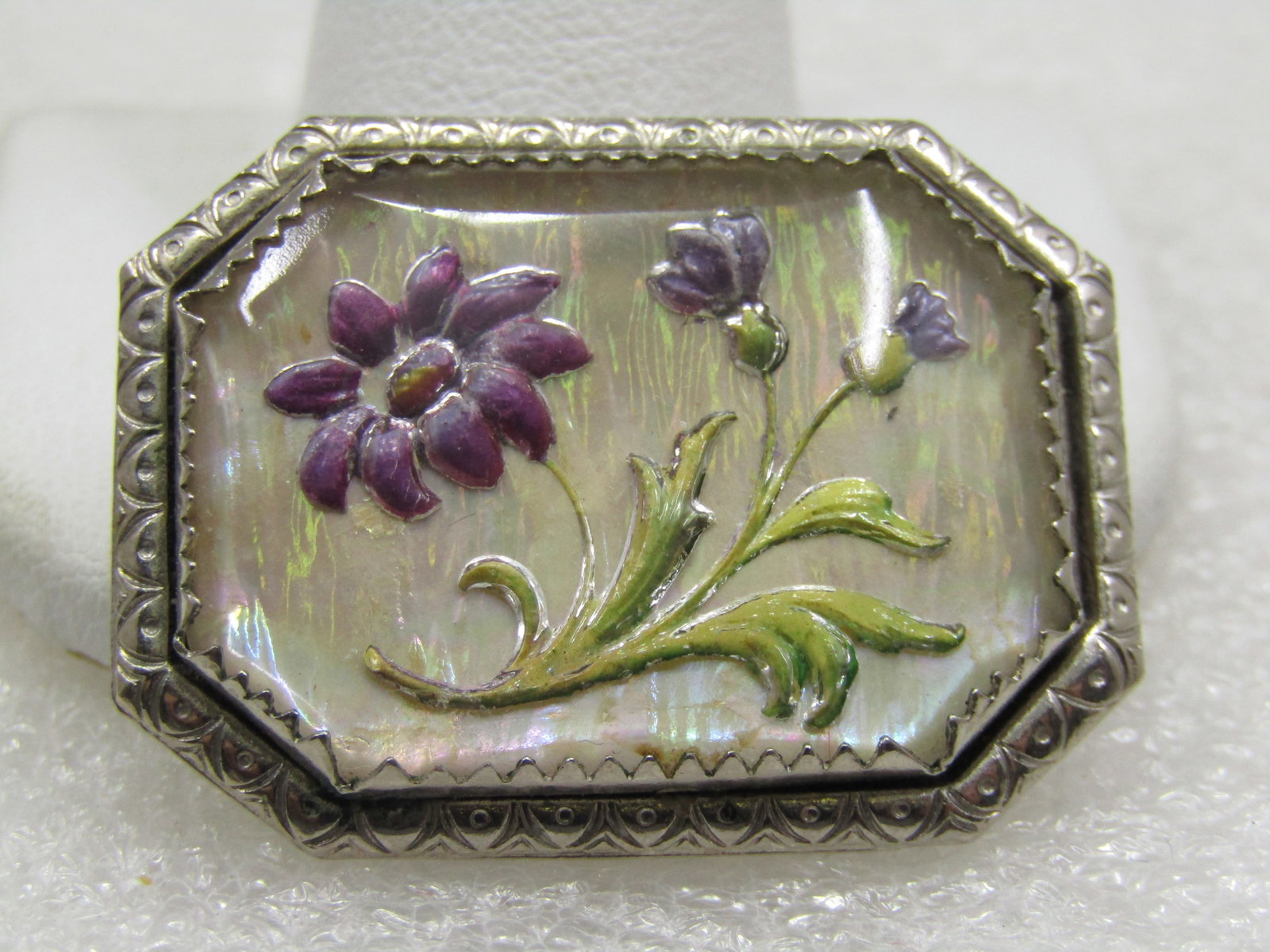 Vintage Reversed Carved Painted Floral Brooch, Framed: Vintage Reversed Carved Painted Floral Brooch, Framed. 1-3/8" by 1" rectangular with cut-corners in a pointed bezel frame with a larger stamped silver tone frame. Bright silvertone that looks like pol