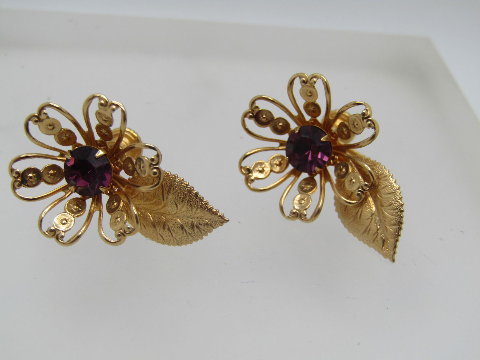 Vintage Purple Rhinestone Floral Earrings, Screwback, 1960's: Vintage Purple Rhinestone Floral Earrings, Screwback, 1960's. These are a filigree blossom with a purple rhinestone that sits lower in the center and a single textured leaf. They are appx. 1.25" by 7/