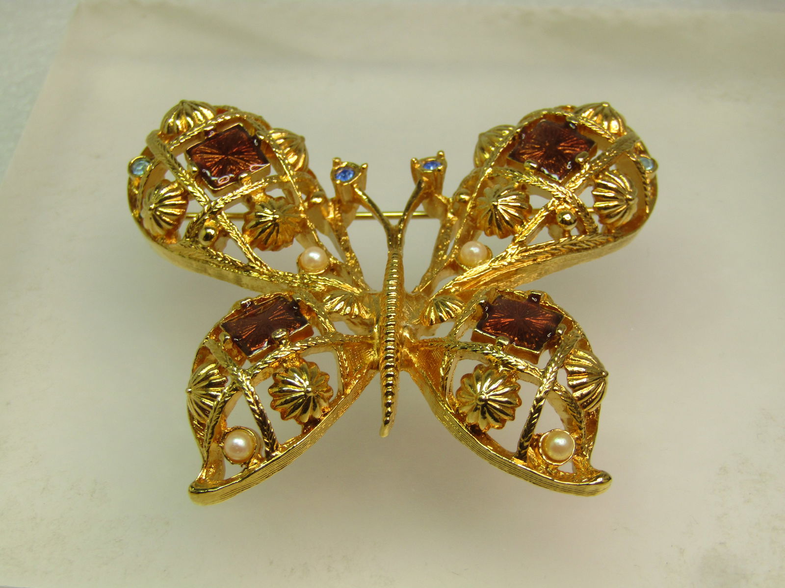 Vintage Enameled, Rhinestone Butterfly Brooch, Faux Pearl, Avon, 1970's: Vintage Enameled, Rhinestone Butterfly Brooch, Faux Pearl, Avon, 1970's. Gold tone with root beer enameled in the wings with blue rhinestone eyes and accents as well as faux pearls. The brooch is