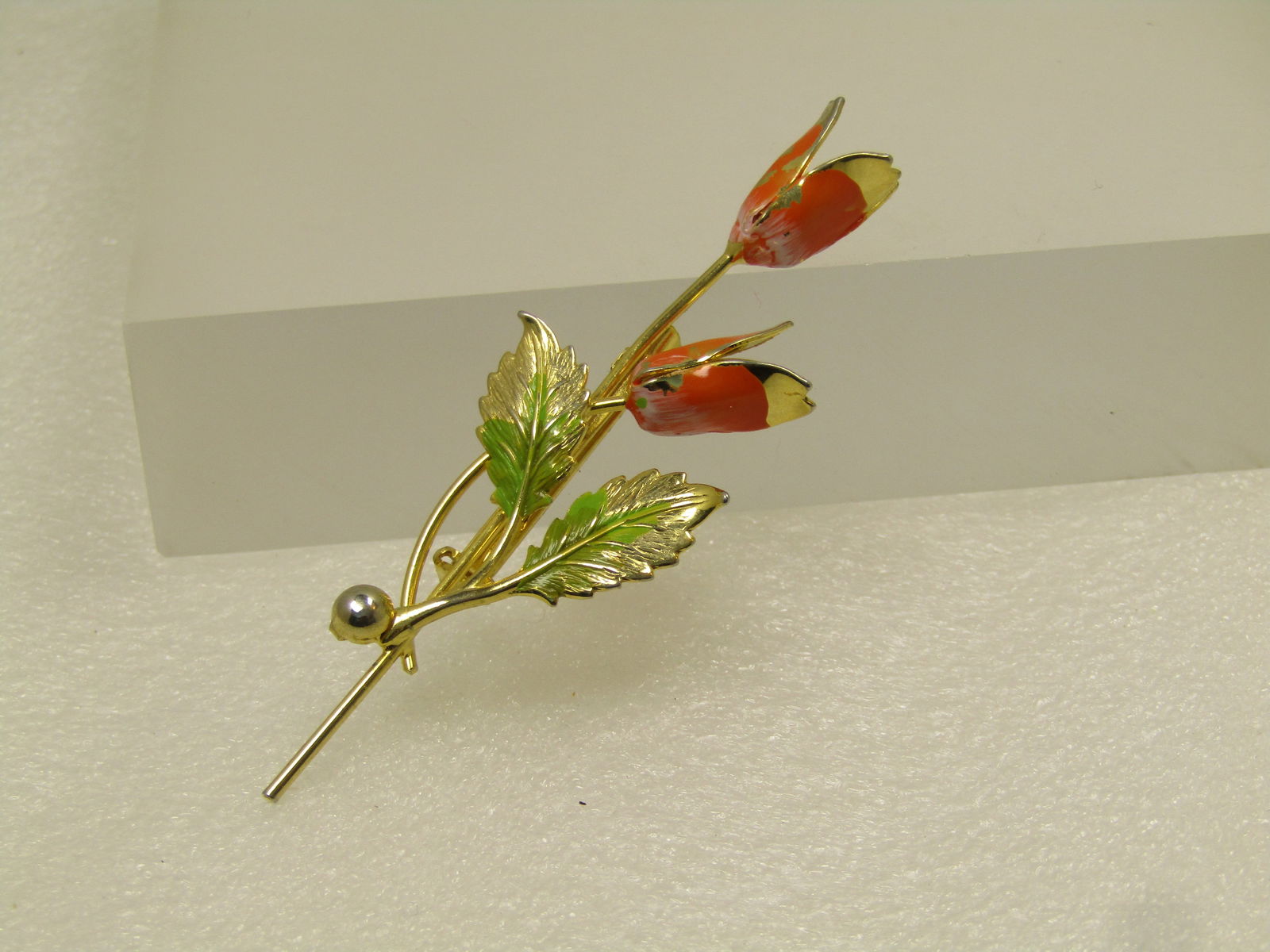 Vintage Orange Green Enameled Floral Brooch, 1960's: Vintage Orange Green Enameled Floral Brooch, 1960's. Two blossom stem brooch with two leaves. Gold tone. Orange ena meling on the outer petals with some wear - also has some white shading toward the b