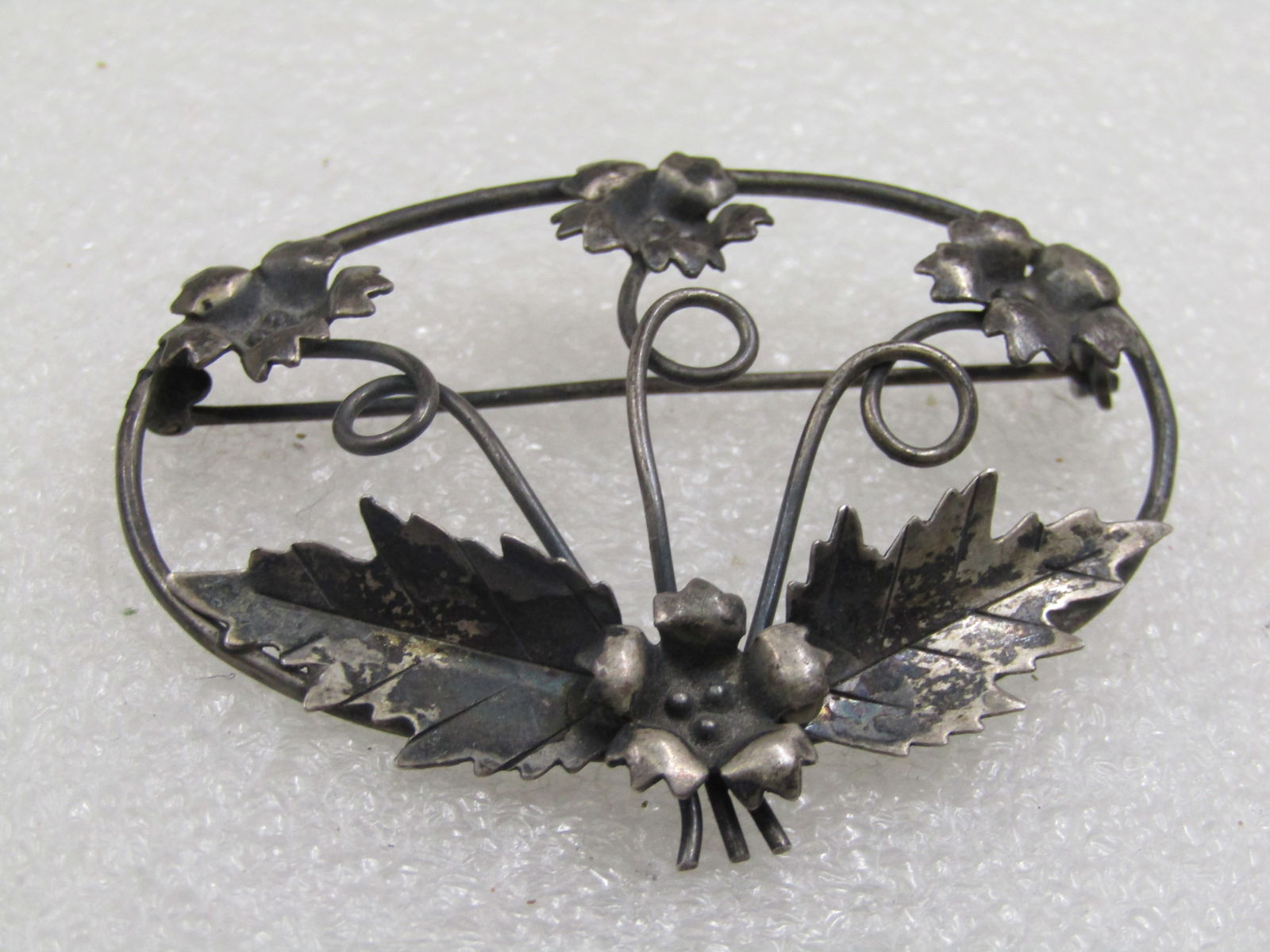 Antique Sterling Floral Brooch, Open Oval Design, 2.25" by 1.5": Antique Sterling Floral Brooch, Open Oval Design, 2.25" by 1.5". Age is appx. 1920's-1930's. Marked sterling, tested and weight is appx. 7.98 gr. Three blossoms with a coiled curved stems and on the b
