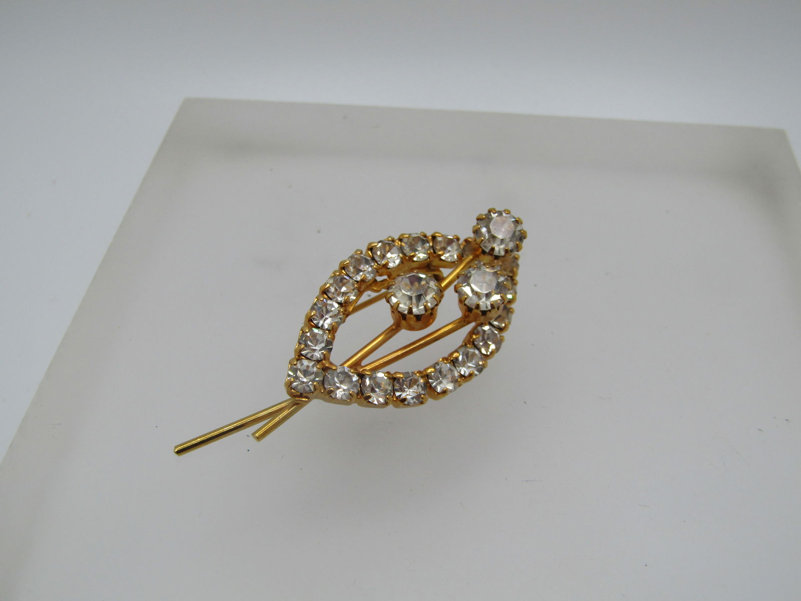 Vintage Rhinestone Brooch, Floral/Leaf Themed, 1960's-1970's: Vintage Rhinestone Brooch, Floral/Leaf Themed, 1960's-1970's. Cat-eye or leaf shaped frame with rhinestones that area ppx. 3.5mm round in square setting with prongs that frame the brooch and three ste