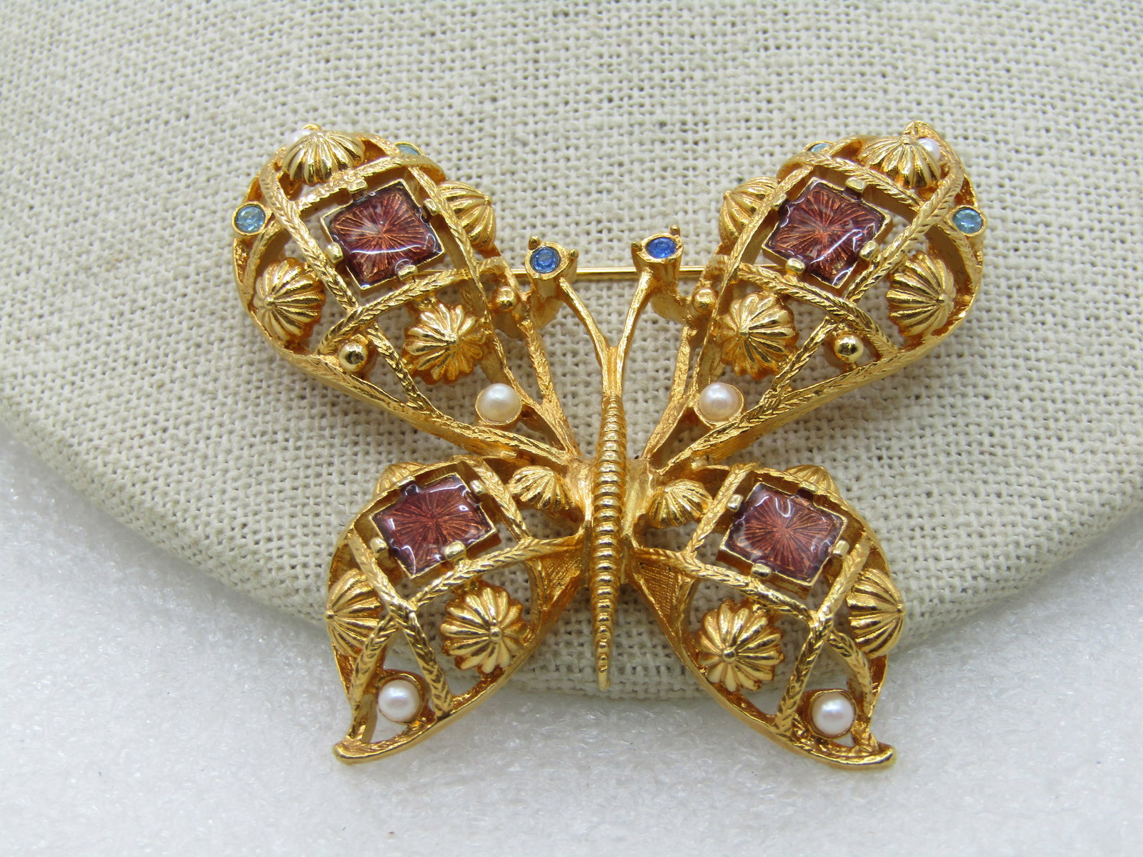 Vintage Avon Butterfly Brooch, Faux Pearl, Rhinestones, Enameling: Vintage Avon Butterfly Brooch, Faux Pearl, Rhinestones, Enameling, 1970's. 2.5" by 2.25" with blue rhinestones and enameld amber colored squares in eadch wing. Open design. Signed. Very good Condition