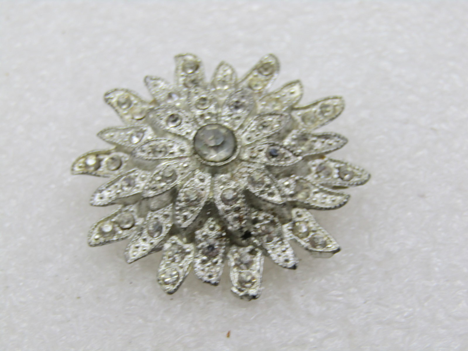 Vintage Rhinestone Floral Blossom Brooch, 1920's, C-Clasp. 1.5": Vintage Rhinestone Floral Blossom Brooch, 1920's, C-Clasp. 1.5". Silver tone pot metal that is still bright and shiny on front and back. Tiered two levels of petals and a center large rhinestone. Ther