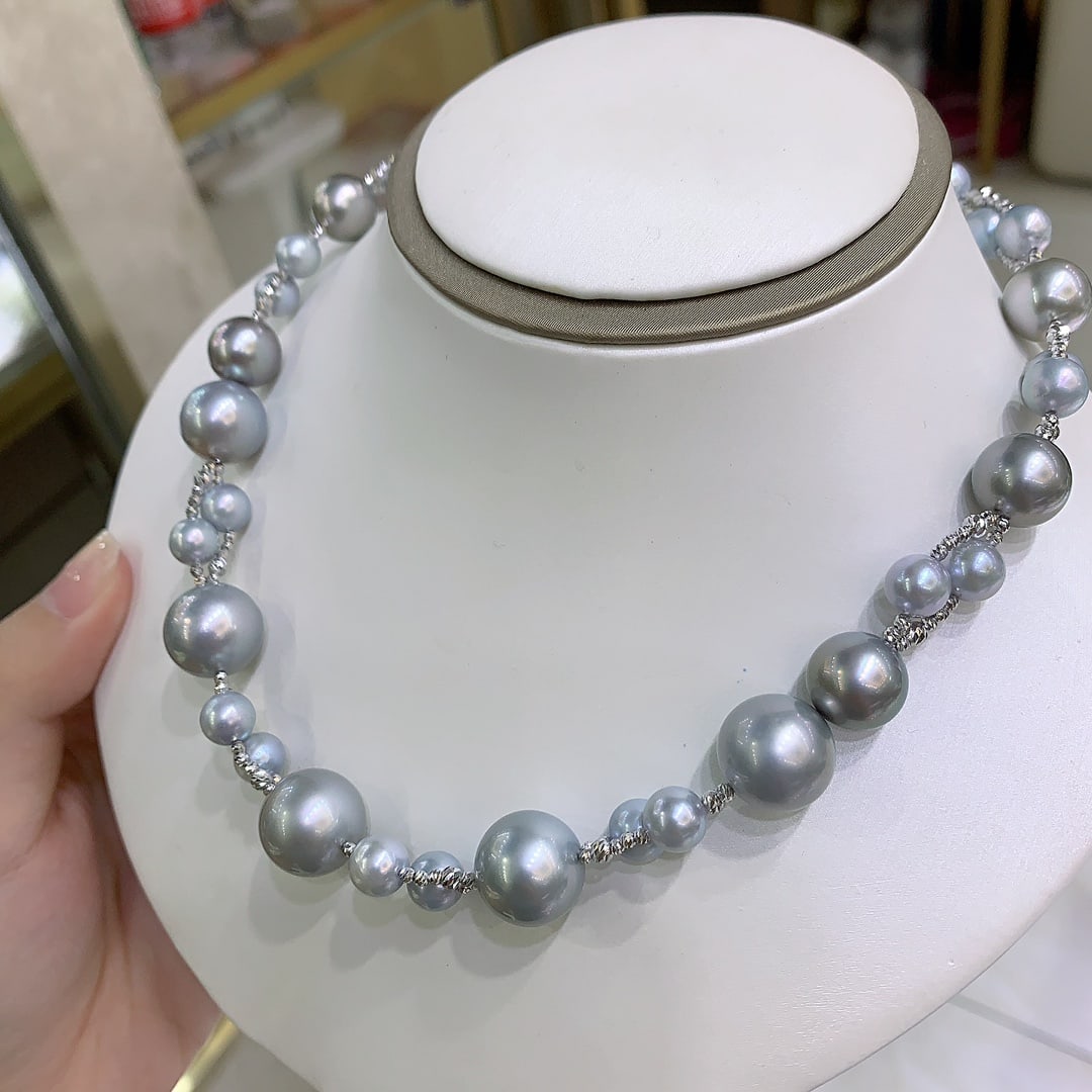 Pearl Necklace: Title: Pearl Necklace Description: This exquisite pearl necklace showcases a stunning blend of delicate light-toned pearls, offering an air of sophistication and timeless elegance. The pearls, ranging
