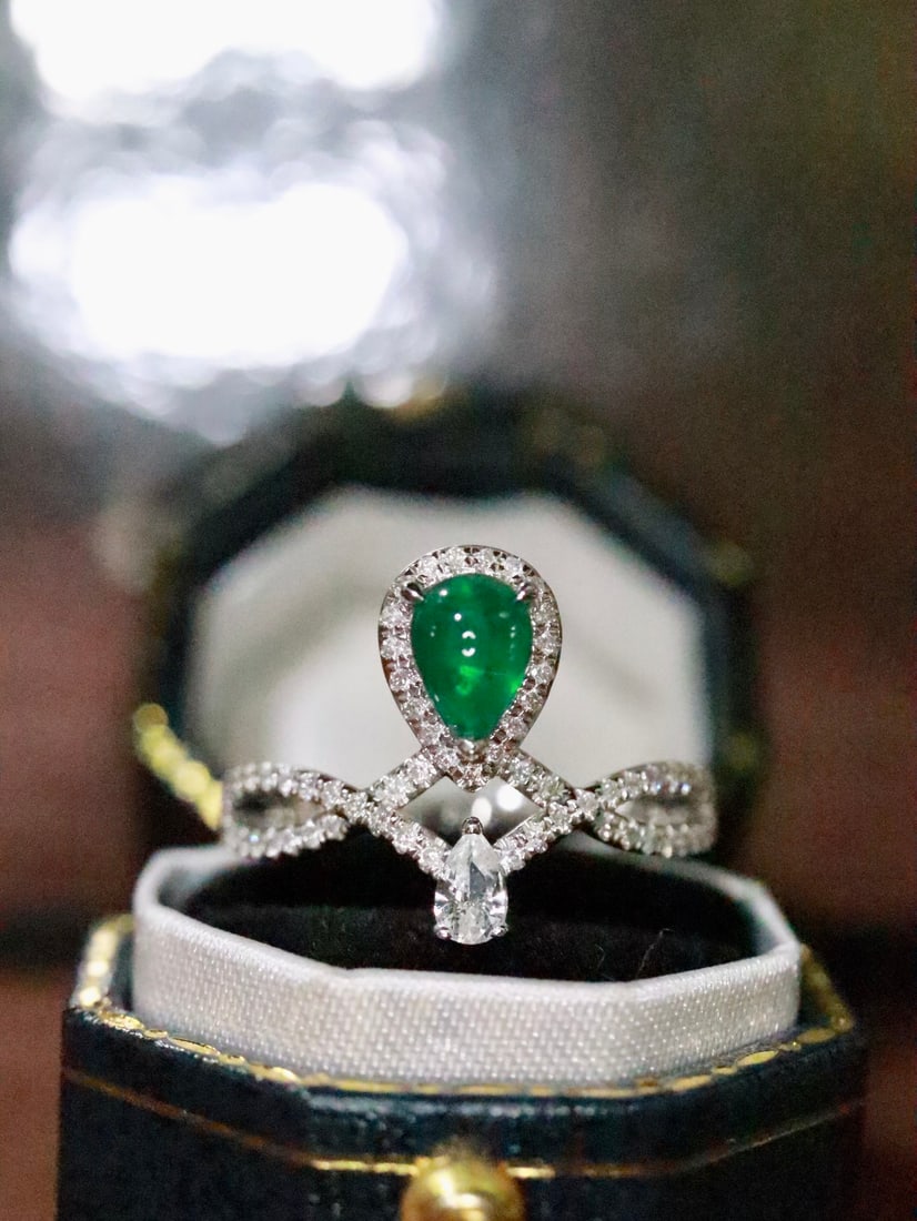 18K Gold Emerald Ring: Title: 18K Gold Emerald Ring Description: This 18K Gold Emerald Ring captivates with its vibrant allure, instantly drawing the eye to its lush, vivid green hue. The emerald's full-bodied, flawless gla