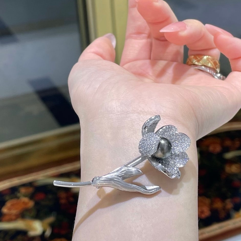 Tahitian Pearl Brooch: Title: Tahitian Pearl Brooch Description: This exquisite brooch features a mesmerizing Tahitian pearl, celebrated for its natural allure and sophisticated charm. The pearl, ranging from 8 to 9mm,