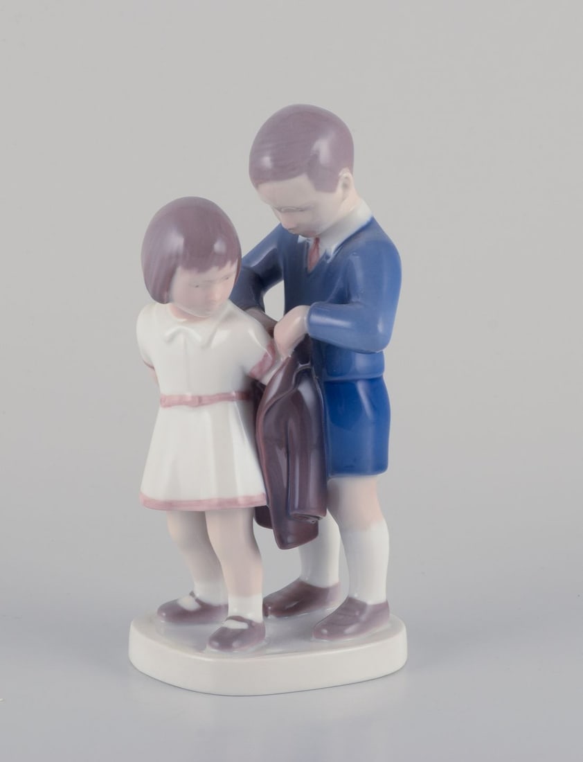 Bing & Grondahl, porcelain figurine. Boy helping girl with her jacket. Ca. 1930s: Title: Bing & Grondahl, porcelain figurine. Boy helping girl with her jacket. Ca. 1930s Description: Bing & Grondahl, porcelain figurine. Boy helping girl with her jacket. Model number 2312. Circa 193