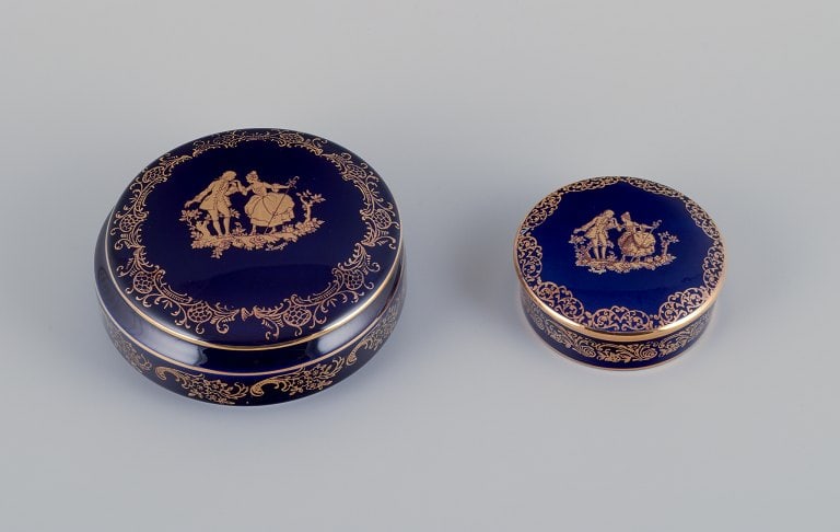 Limoges, France. Two round covered jars in porcelain decorated with 22-karat gold leaf and beautiful: Title: Limoges, France. Two round covered jars in porcelain decorated with 22-karat gold leaf and beautiful royal blue glaze. Scène galante. Description: Limoges, France. Two round covered jars i