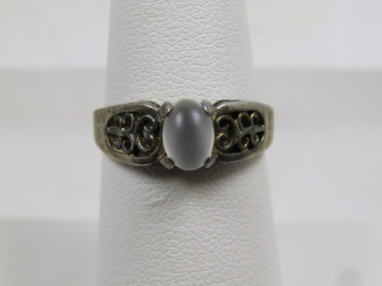 Vintage Sterling White Cateye Ring, Scrolled, Sz. 7, 1960's-1970's: Vintage Sterling White Cateye Ring, Scrolled, Sz. 7, 1960's-1970's. The ring has a white oval cateye stone on top - likely glass. The stone is appx. 6.5mm by 4.5mm. It has an open work scroll one
