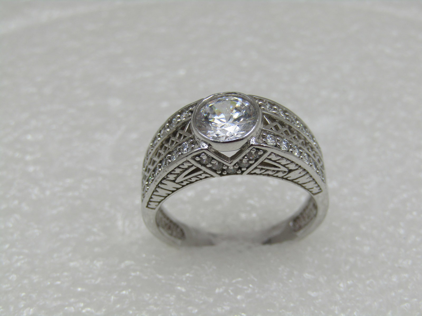 Sterling CZ Domed Ring, Sz. 10.25, Diamoniquem 8mm: Sterling CZ Domed Ring, Sz. 10.25, Diamoniquem 8mm bezel-set main stone set in the top of the dome with open V on front and back and 5 1mm czs arranged outlining the V in a V pattern on front and back