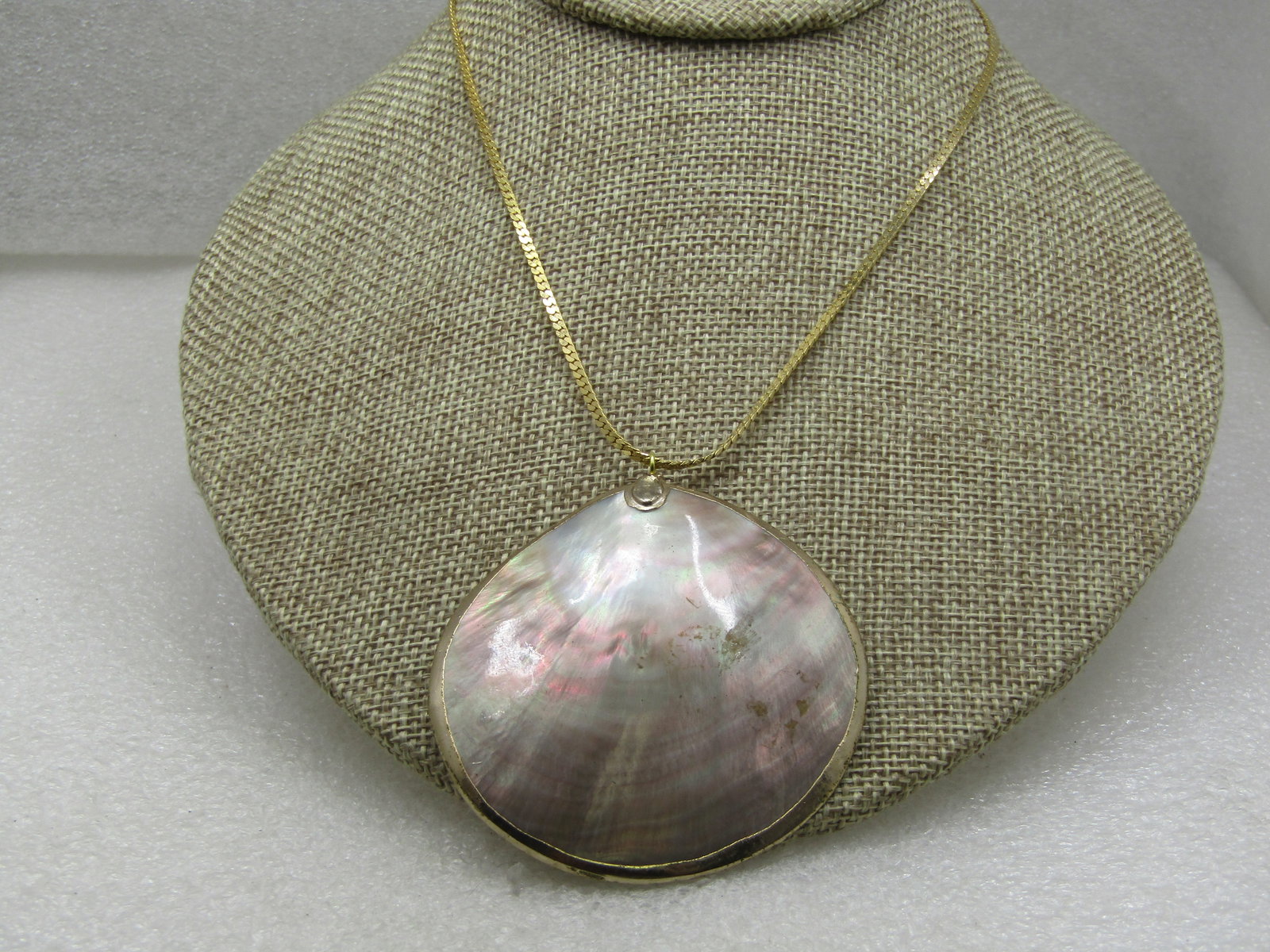 Vintage Large Shell Necklace 16" Herringbone Chain: Vintage Large Shell Necklace 16" Herringbone Chain. The shell has a gold metal edge around the edge. It is appx. 2.5" across with a slight dome as shells have. This is in mother-lf-pearl white and goe