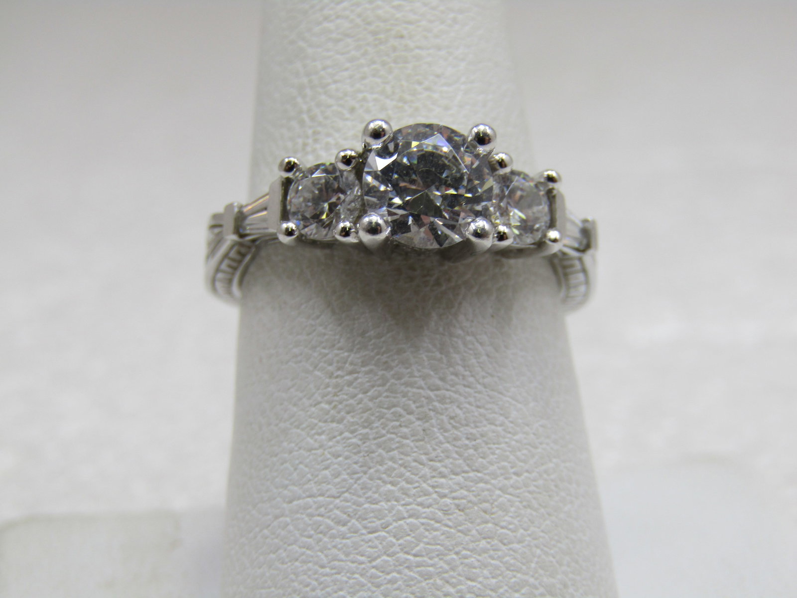 Sterling Diamonique CZ Engagement Ring, Sz. 8.25, Multi-Stones: Sterling Diamonique CZ Engagement Ring, Sz. 8.25, Multi-Stones. 1 CTW main round cz that sits highers with an appx. 1/3 ct cz on each side and then a tapered baguette on each side of that stone. The b