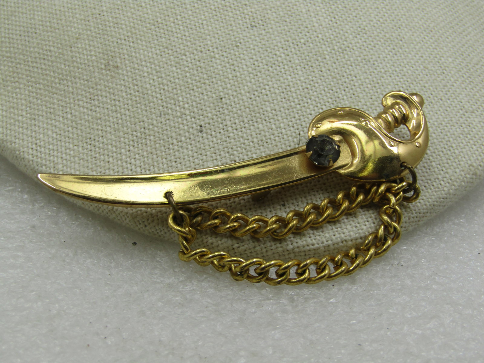 Vintage Coro Sword With Chain Brooch, Smoky Rhinestone, Mid-Century: Vintage Coro Sword With Chain Brooch, Smoky Rhinestone, Mid-Century. This is gold tone with a double drape of curb link chain that hangs down from the sword. The chain is appx. 5mm wide. The sword is