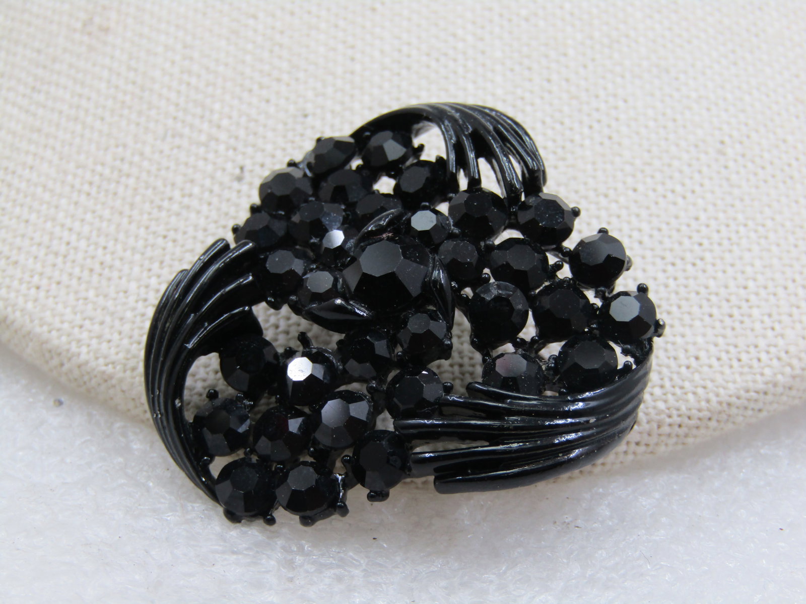 Vintage Black Rhinestone & Metal Brooch, 1.5", 1960's: Vintage Black Rhinestone & Metal Brooch, 1.5", 1960's. It has a triangular design with curved strands and blossom cluster of black rhinestones. The pin is painted black metal. Not signed by the maker.