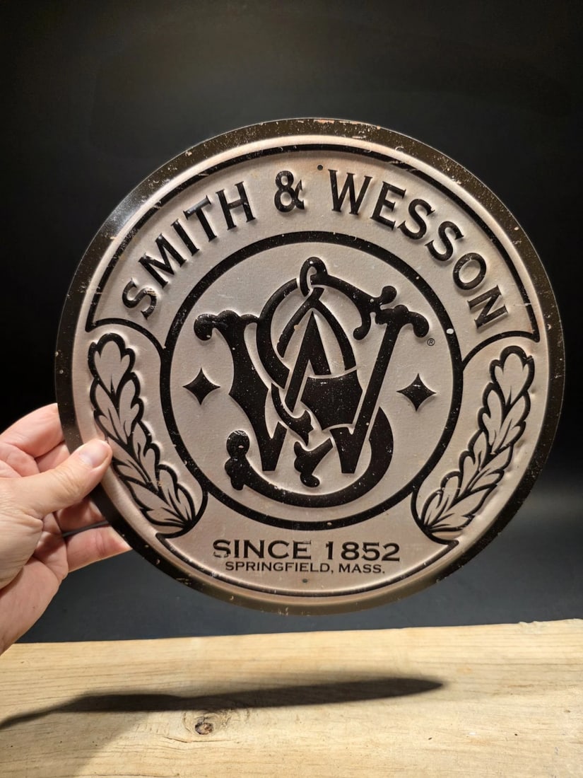 11 1/2" Round Metal Smith & Wesson Sign: 11 1/2" Such a neat reproduction metal Vintage style sign.A Legacy of American Craftsmanship Pay tribute to the heritage of the "Modern Americana Revival" with this distressed Smith & Wesson Metal Sig