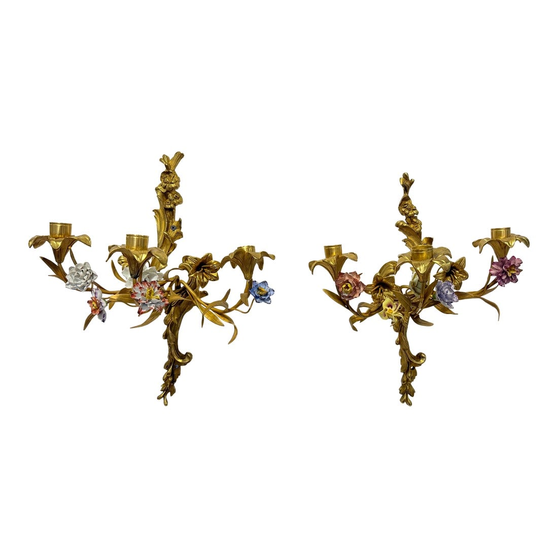 Pr, French Rococo Revival Gilt Bronze Sconces With Porcelain Flowers, 19th C: This refined pair of French wall-mounted candle sconces is fashioned in gilt bronze and conceived in the Rococo Revival manner popular in the 19th century, with asymmetrical rocaille backplates issuin